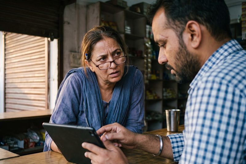 A shop owner and her colleague looking at the day's results on a tablet after closing